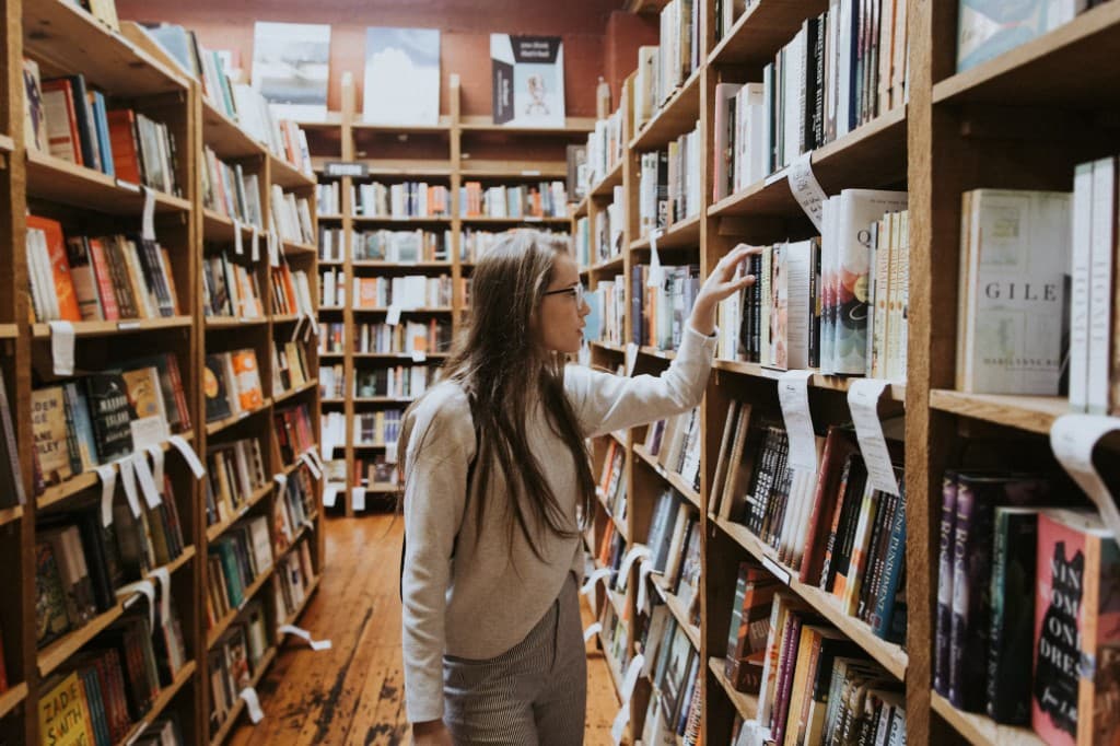 Woman choosing a book from library shelves