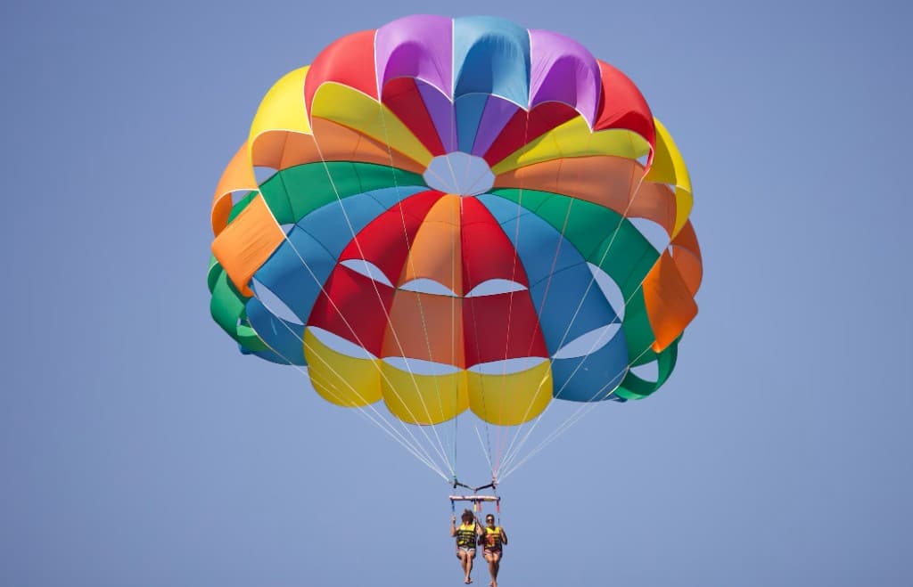 Two people parasailing under a colourful parachute