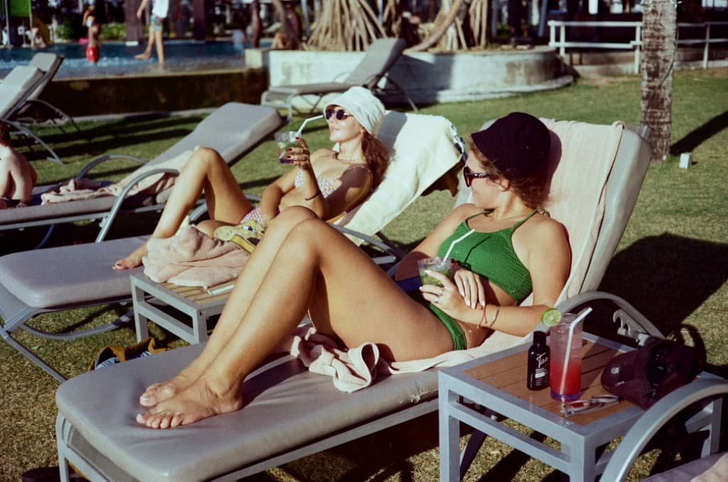 Two women relaxing on sun loungers by a pool